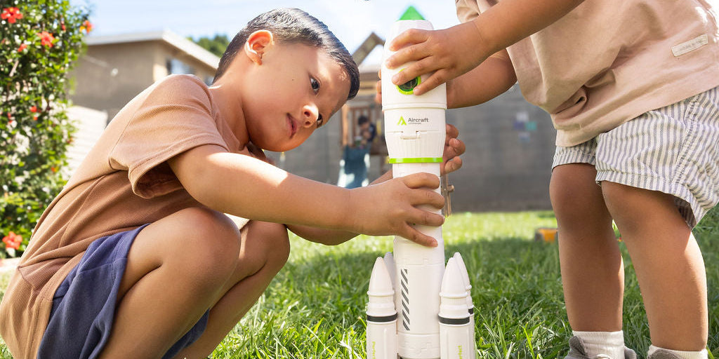 Two children playing with a toy rocket ship outdoors