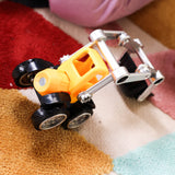 A small toy construction vehicle with a yellow body, black wheels, and a silver metal front loader arm, photographed on a multicolored textured rug.