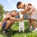 Two children playing with a toy rocketship in a grassy outdoor area.